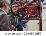 Experienced technician analyzing complex electrical wiring with clipboard in brightly lit workspace