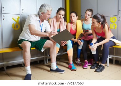 Experienced trainer with document showing the last results to his team at break
