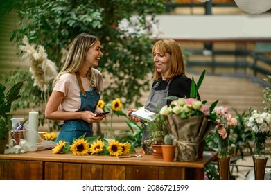 Experienced woman florist helping young employee with a smartphone how their business works and how to deal with customers - Powered by Shutterstock