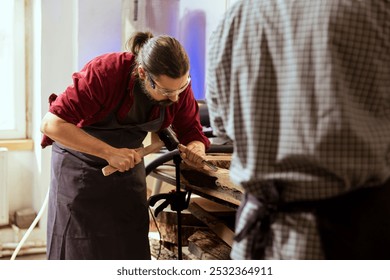 Experienced woodworker shaping raw timber using chisel and hammer in carpentry shop, enjoying diy hobby. Woodworking professional in studio shaping wooden pieces with tools, making wood sculptures - Powered by Shutterstock