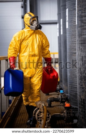 Experienced worker carrying canisters with acid inside chemicals factory.