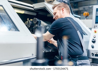 Experienced worker changing tool setup of lathe machine on the factory floor - Powered by Shutterstock