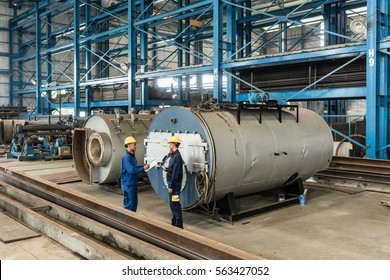 Experienced worker writing observations while checking the quality of manufactured industrial boilers