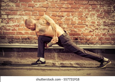 Experienced yoga man doing various yoga poses outdoor by the brick wall. Yoga concept. 