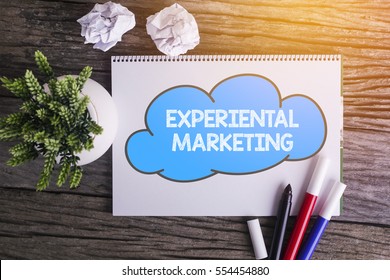 EXPERIENTAL MARKETING word with Notepad and green plant on wooden background