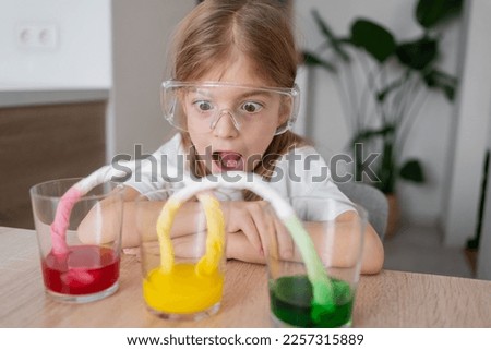 Experiment at home with food color for kids.  Early development. Chemical and scientific experiments or observations. Kid girl having classes at home enjoying art.