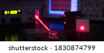 Experiment in optic lab with laser device. Red laser on optical table in physics laboratory