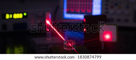 Experiment in optic lab with laser device. Red laser on optical table in physics laboratory