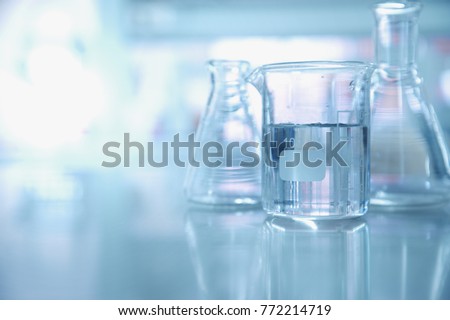 experiment water in beaker and flask in blue chemistry science laboratory background