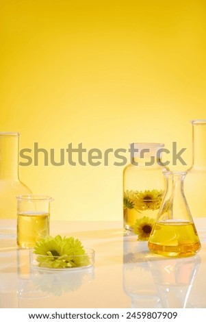 Experimental instruments containing light yellow color essential oil over yellow background, decorated by some fresh calendula flowers. Vacant space for adding text. front view