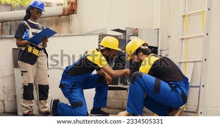 Expert african american technician cleaning layer of dirt and dust from condenser compressor coils while colleague uses manometers to check for refrigerant leaks and read pressure in hvac system