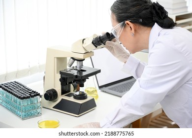 An Expert Asian Aged Female Scientist Or Medical Chemist Supervisor Examining A Virus Specimen Under A Microscope While Working In The Lab. Close-up Image