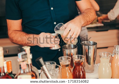The expert bartender is making a cocktail at the home party. Man preparing cocktails.
