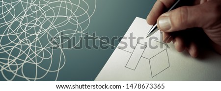 Expert business hand solving tangled line, outside the paper sheet on a blue desk