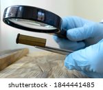 Expert in criminology through magnifying glass examines a bullet case