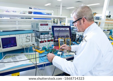 An expert engineer working at the electrical test bench next to an oscilloscope