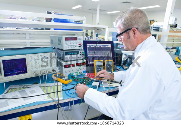 An expert engineer working at the electrical\
test bench next to an\
oscilloscope