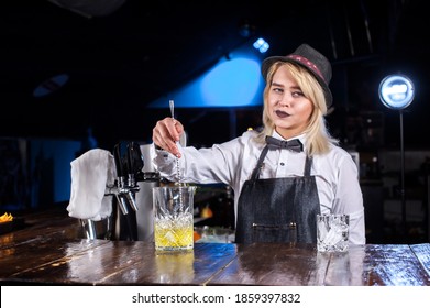 Expert girl bartender decorates colorful concoction on the bar