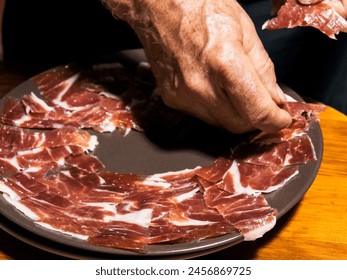 Expert hands artfully arrange thin slices of jamon on a plate. - Powered by Shutterstock