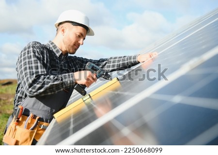 Expert is inspecting quality of a solar batterys. Worker in uniform and helmet with equipment. Ecology power conservation concept