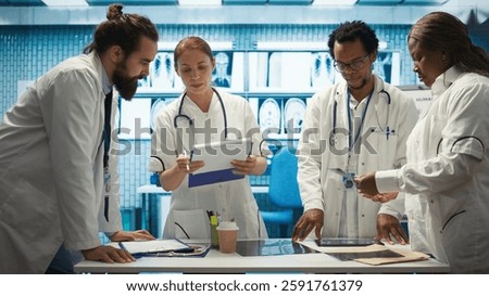Expert physicians comparing test results and healthcare records in cabinet, consulting colleagues for disease prevention. Diverse medics sharing their professional expertise in a meeting. Camera B.