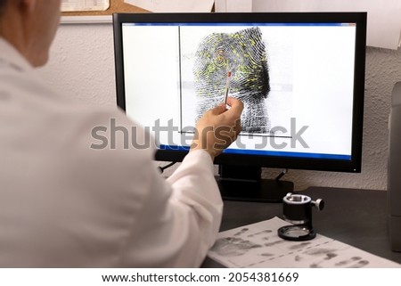 An expert in police science, csi, checks a fingerprint and its matching points on a computer screen