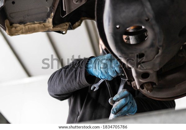 Expert senior mechanic repairing a car after a
street crash. Details and focus on metal parts and electric wires.
Blurred background, natural light. Occupation and job concept.
Sabotage and crime.