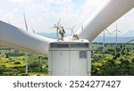 Expert team maintaining and inspecting wind turbines efficient clean energy production. surrounded by vast green fields and distant mountains, with multiple turbines spinning under partly cloudy sky.