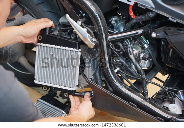 Expert technician install radiator to motorcycle\
or scooter,radiator is main component of the cooling system and to\
keep the engine from overheating,motorcycle repair, maintenance and\
service concept
