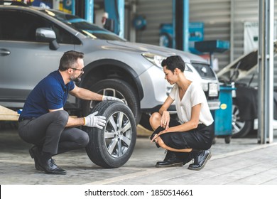 Expertise Mechanic Man Showing The Tread Of A Old Tire To A Female Customer At Car Maintenance And Auto Service Garage