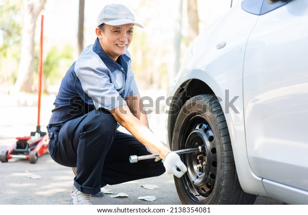 Expertise\
mechanic man  in uniform using force trying to unscrew the wheel\
bolts nuts and help a woman for changing car wheel on the highway,\
car service, repair, maintenance\
concept.