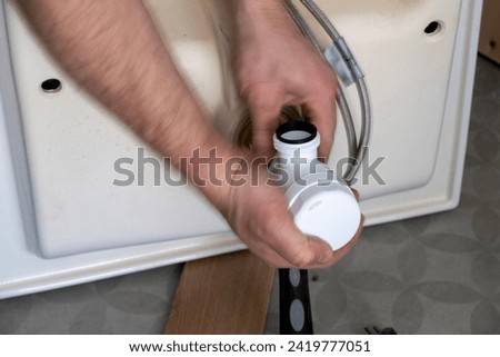 Expertly captured moment of a Man skillfully installing a drain to the sink for efficient water management.
