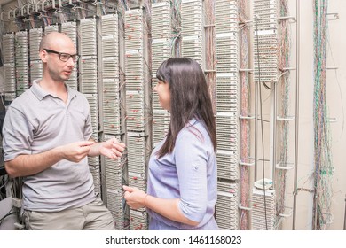 Experts Are Talking In The Server Room. A Team Of People Chatting In A Datacenter. Men And Women Discuss Ip Telephony Issues Near The Network Switching Patch Panel. 