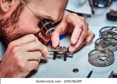 Expirienced clockmaster is fixing old watch for a customer at his repairing workshop.