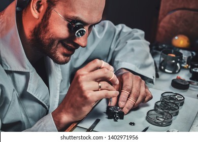 Expirienced clockmaster is fixing old watch for a customer at his repairing workshop.