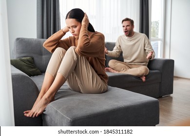 Explain It. Young Emotional Strict Man Feeling Jealous, Waiting For Explanations And Looking At His Wife Ignored Him While Closing Her Ears With Her Hands