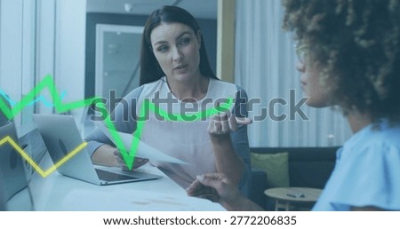Explaining advisor wearing blouse holding papers and gesturing at office table, laptop, data charts. Business, collaboration, professional, modern, sunlit, minimalist, boardroom