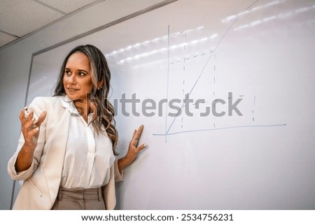 Explaining graph on whiteboard during presentation, businesswoman speaker