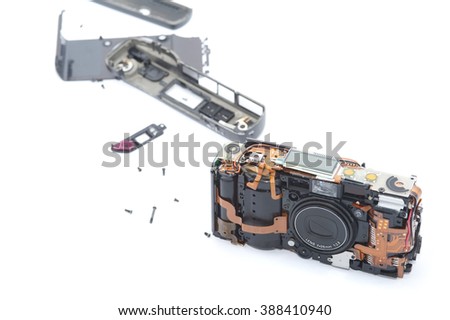 Exploded or dismantled camera laying on white background with various pieces trailed behind it