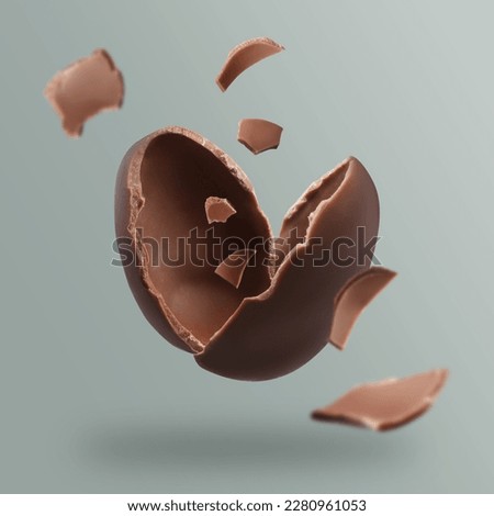 Exploded milk chocolate egg on grey background