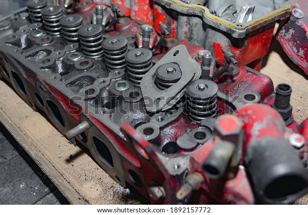 Exploded view of the cylinder head of\
a four-cylinder engine being repaired in a car\
workshop.