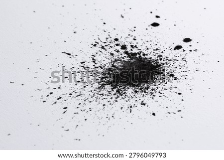 Exploding black ink splatter on white surface