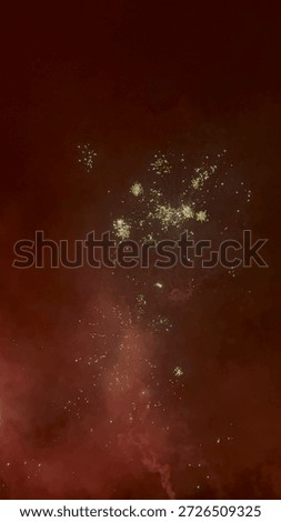 Exploding fireworks against a deep red misty night sky. Festive pyrotechnic display with sparks and smoke during celebration.