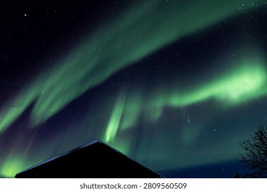 Exploding green northern lights over a roof in Fairbanks alaska