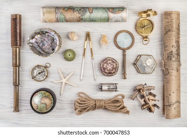 Exploration and nautical theme grunge background. Compass, telescope, sextant, divider, old coins, rope, shell, map, globe, magnifier, hourglass on wood desk. Retro style.