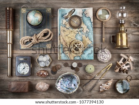 Exploration and nautical theme grunge background. Compass, telescope, sextant, divider, old coins, rope, shell, map, globe, magnifier, hourglass on wood desk. Retro style.