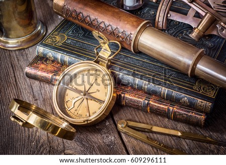 Exploration and nautical theme grunge background. Compass, telescope, sextant, divider and old book on wood desk.