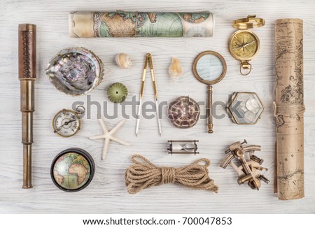 Exploration and nautical theme grunge background. Compass, telescope, sextant, divider, old coins, rope, shell, map, globe, magnifier, hourglass on wood desk. Retro style.