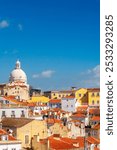 Explore the charming streets of Lisbon with the dome of Santa Engracia church rising above colorful rooftops on a clear day.