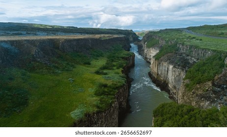 Explore the dramatic cliffs and verdant greenery surrounding a winding river in Icelands majestic canyon. This tranquil location showcases natures artistry and pristine wilderness. Gullfoss